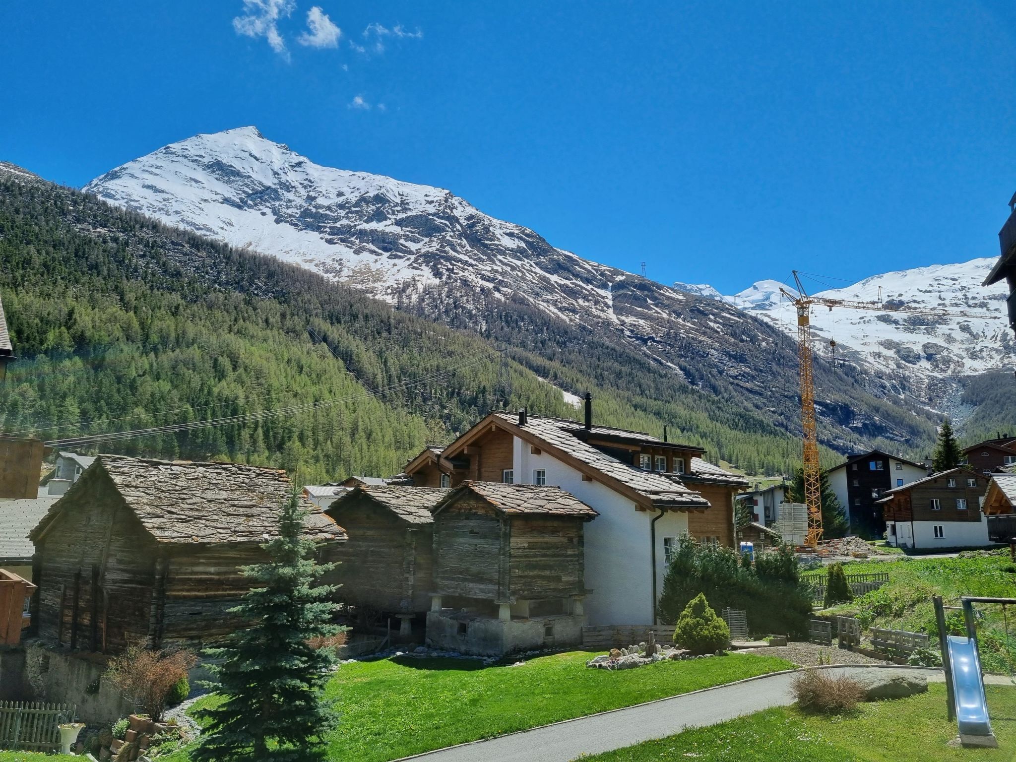 Un paysage montagneux avec un télésiège, des bâtiments en bois et un ciel dégagé.
