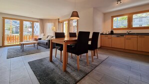 Eine moderne Küche mit Essbereich, großen Fenstern und Blick ins Freie.