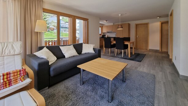 Ein modernes Wohnzimmer mit einer Couch, einem Couchtisch und einem Essbereich mit Stühlen und einem Tisch.