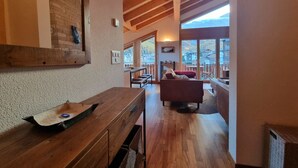 Un interior de madera con zona de comedor, un sofá y vistas al exterior.