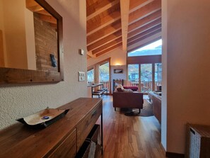 Ein Holzinnenraum mit Essbereich, einer Couch und Blick nach draußen.
