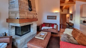 Una sala de estar acogedora con chimenea de piedra, sofás de cuero y techo de madera.