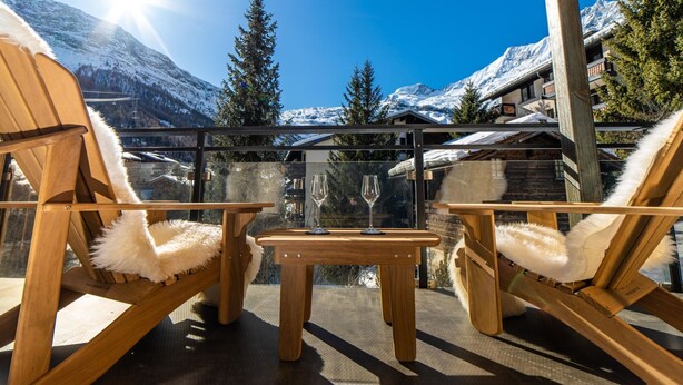 A wooden deck with two chairs and a table, overlooking a snowy mountain landscape. - Riverside 24 Appartement/Fewo Appartement/Fewo by Interhome (Saas-Fee)