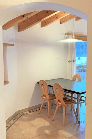 A dining area with a table and chairs, a hanging light fixture, and a view of the outdoors. - Dominic B Appartement/Fewo 4-Bettwohnung by Interhome (Saas-Fee)
