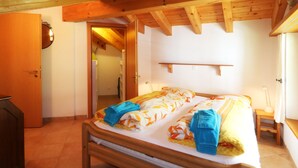 Une chambre à coucher avec un lit en bois, une table de chevet, une lampe et une porte donnant sur une autre pièce.