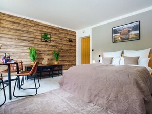 Un dormitorio moderno con una cama grande, un escritorio con sillas y una pared de acento de madera.