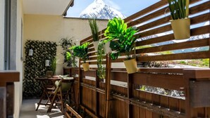 A balcony with wooden slats, potted plants, a table with chairs, and a view of a snow-capped mountain. - Falke EG Appartement/Fewo Greenspot Apartment by Interhome (Saas-Fee)