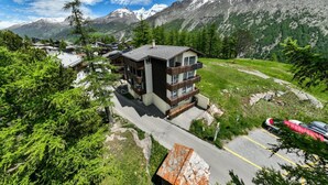 A modern multi-story building with balconies, surrounded by lush greenery and mountains. - Falke EG Appartement/Fewo Greenspot Apartment by Interhome (Saas-Fee)