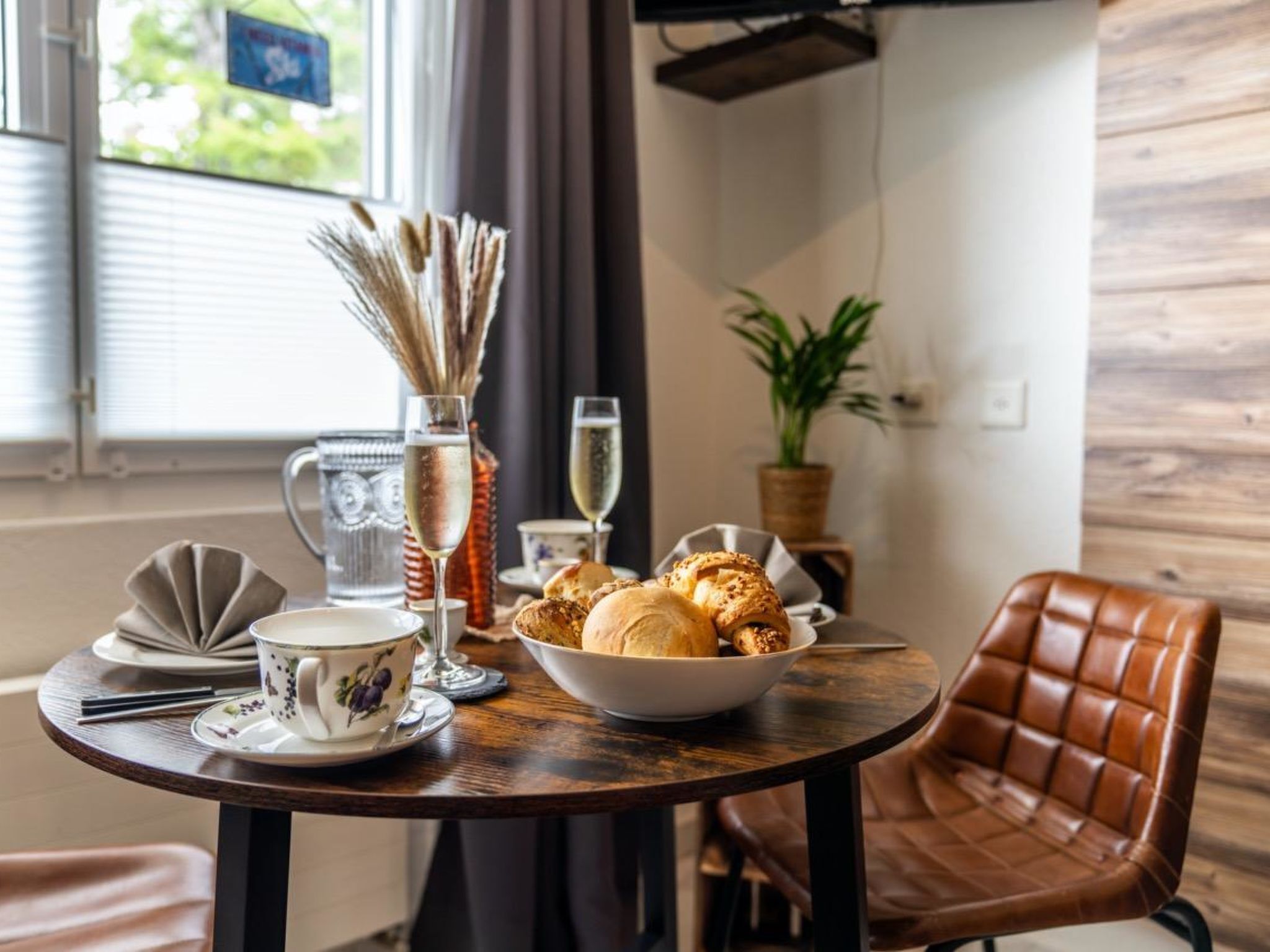 Ein Esstisch mit Brot in einer Schüssel, einem Weinglas und einer Tasse.