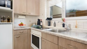 A compact kitchen with wooden cabinets, a built-in oven, a sink, and a window with a view. - Falke EG Appartement/Fewo Greenspot Apartment by Interhome (Saas-Fee)
