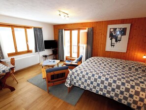 Ein gemütliches Zimmer mit einem Bett, einem Schreibtisch, einem Sessel und einem Fernseher.