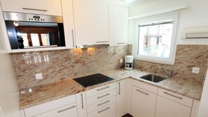 Una cocina compacta con horno integrado, cafetera y ventana que proporciona luz natural.
