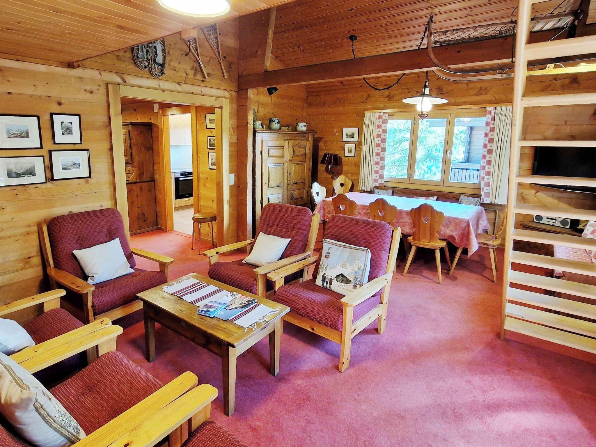 A cozy cabin interior with wooden walls, a dining area, and a television.