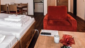 Een hotelkamer met een bed, een bureau, een rode stoel en een tafeltje met een afstandsbediening en een decoratief object.