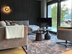 A modern living room with a sofa, a coffee table, and a TV. - Hollywood 1 Appartement/Fewo 6-Bettwohnung by Interhome (Saas-Fee)