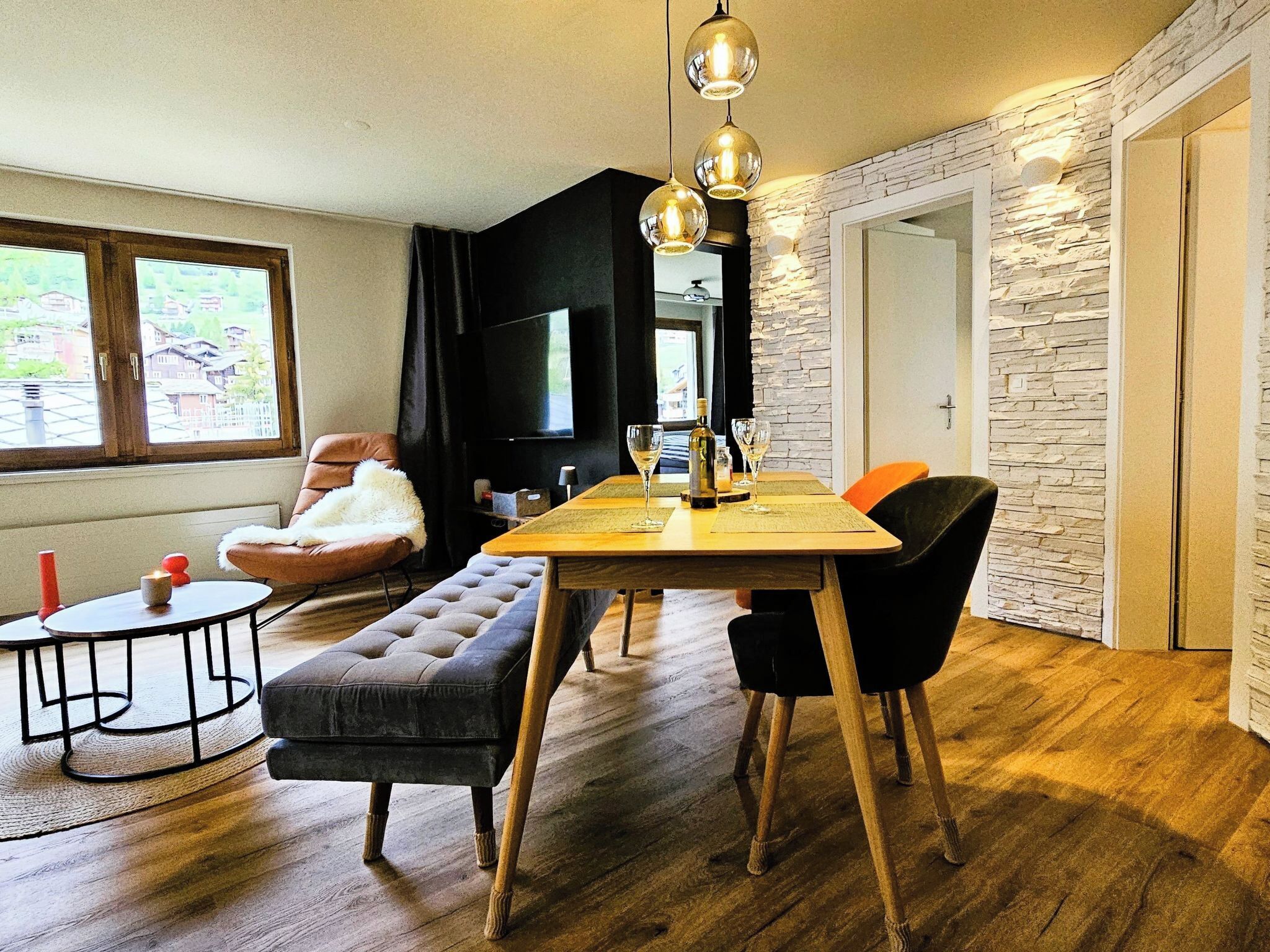 A modern living room with a wooden dining table, a sofa, and a TV.
