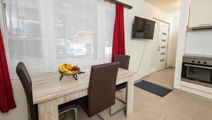 Una cucina moderna con forno integrato, un'area pranzo con tavolo e sedie, e una finestra con tende.