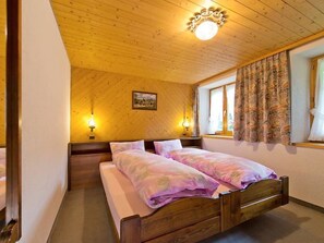 Un dormitorio con dos camas, techo de madera y ventana con cortinas.