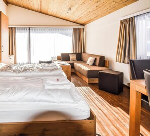 A hotel room with a large bed, a sofa, a small table, and a desk. - Haus Camillo Appartement/Fewo 6-Bettwohnung Nr. 24 by Interhome (Saas-Fee)