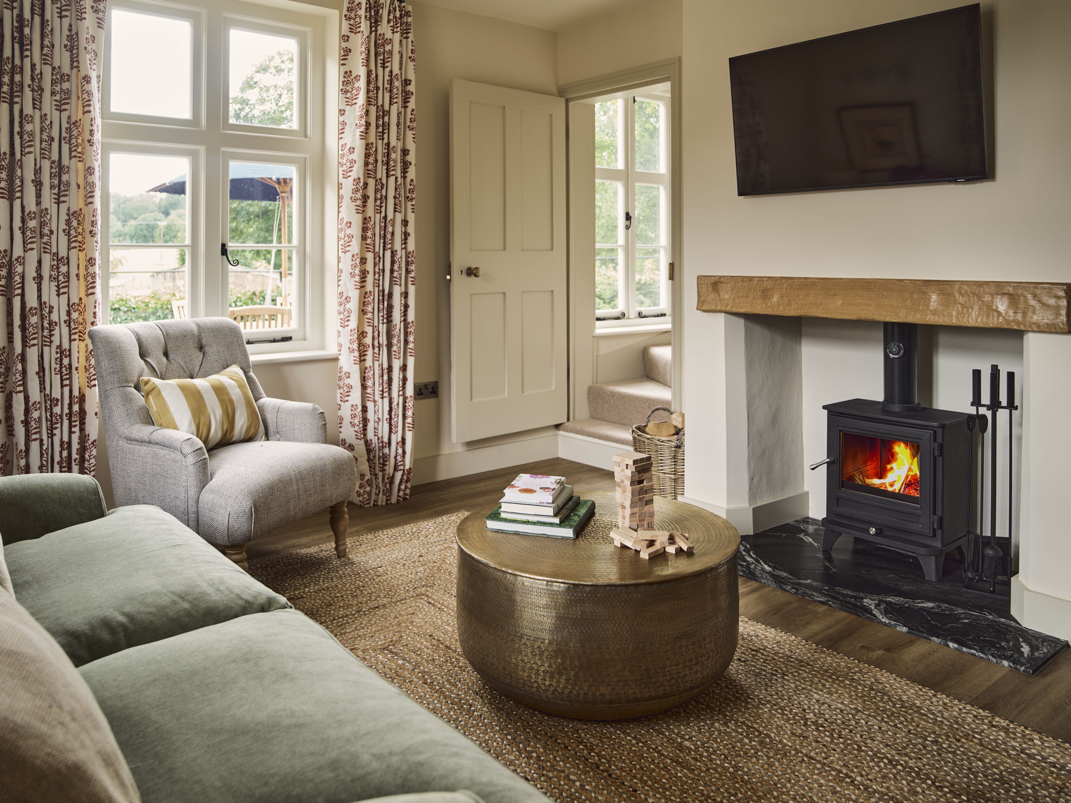 A living room with a sofa, armchair, and a round coffee table. There's a fireplace with a TV mounted above it.