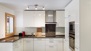 Een moderne keuken met witte kasten, granieten aanrecht, een ingebouwde oven en een raam met uitzicht.