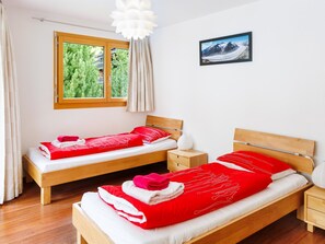 Ein Hotelzimmer mit zwei Betten, einem Fenster mit Blick auf Grünflächen, einem Bild an der Wand und einer weißen Deckenleuchte.