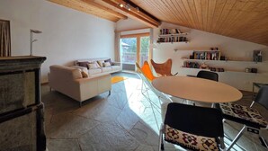 Un salon moderne avec un sol en pierre, un canapé blanc, une table ronde et une bibliothèque.