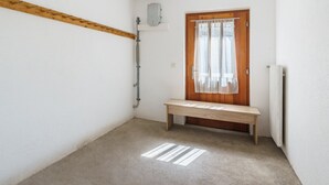 Un corridoio stretto con una panca di legno, un termosifone e una porta con tenda.