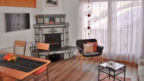 Una sala de estar con chimenea, techo de madera, una mesa de comedor con sillas, un sofá y una mesa de centro de vidrio.