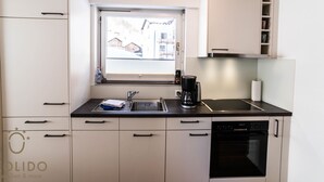 Eine kleine Küche mit Fenster, Kaffeemaschine und Geschirrspüler.