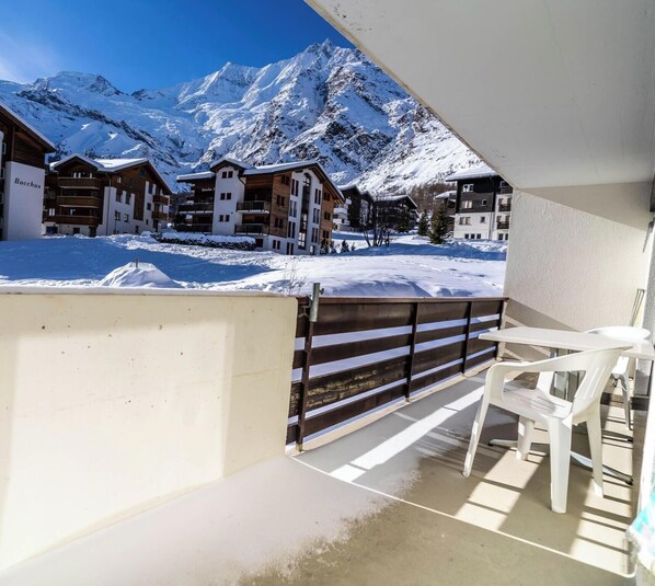 Un balcón con vista a montañas nevadas y un edificio con el letrero 'Bacchus'.