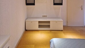 A bedroom with a wooden ceiling, a white wall unit with storage, a bed, and a door.