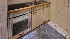 A compact kitchen with a stove, oven, sink, and cabinets.