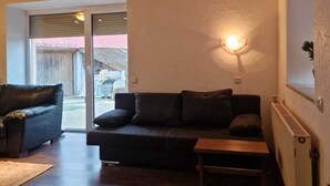 A modern living room with a dark sofa, a wooden coffee table, and a wall-mounted light fixture.