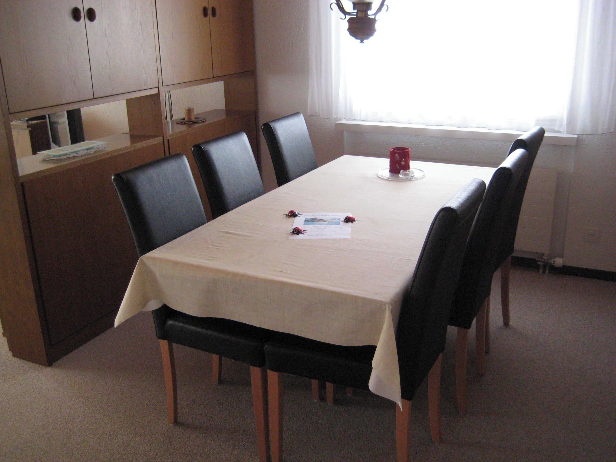 A dining area with a table, chairs, and a window with curtains.