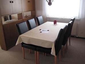 Ein Essbereich mit Tisch, Stühlen und einem Fenster mit Vorhängen.