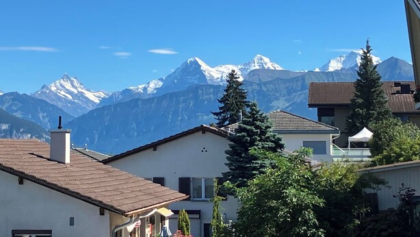 Zona residencial con casas, árboles y una cadena montañosa al fondo.