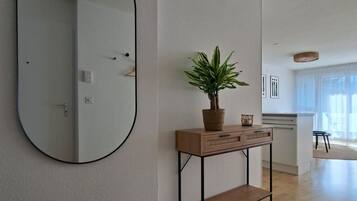 Un salon moderne avec un grand miroir, une console en bois agrémentée d’une plante et un tapis rond.