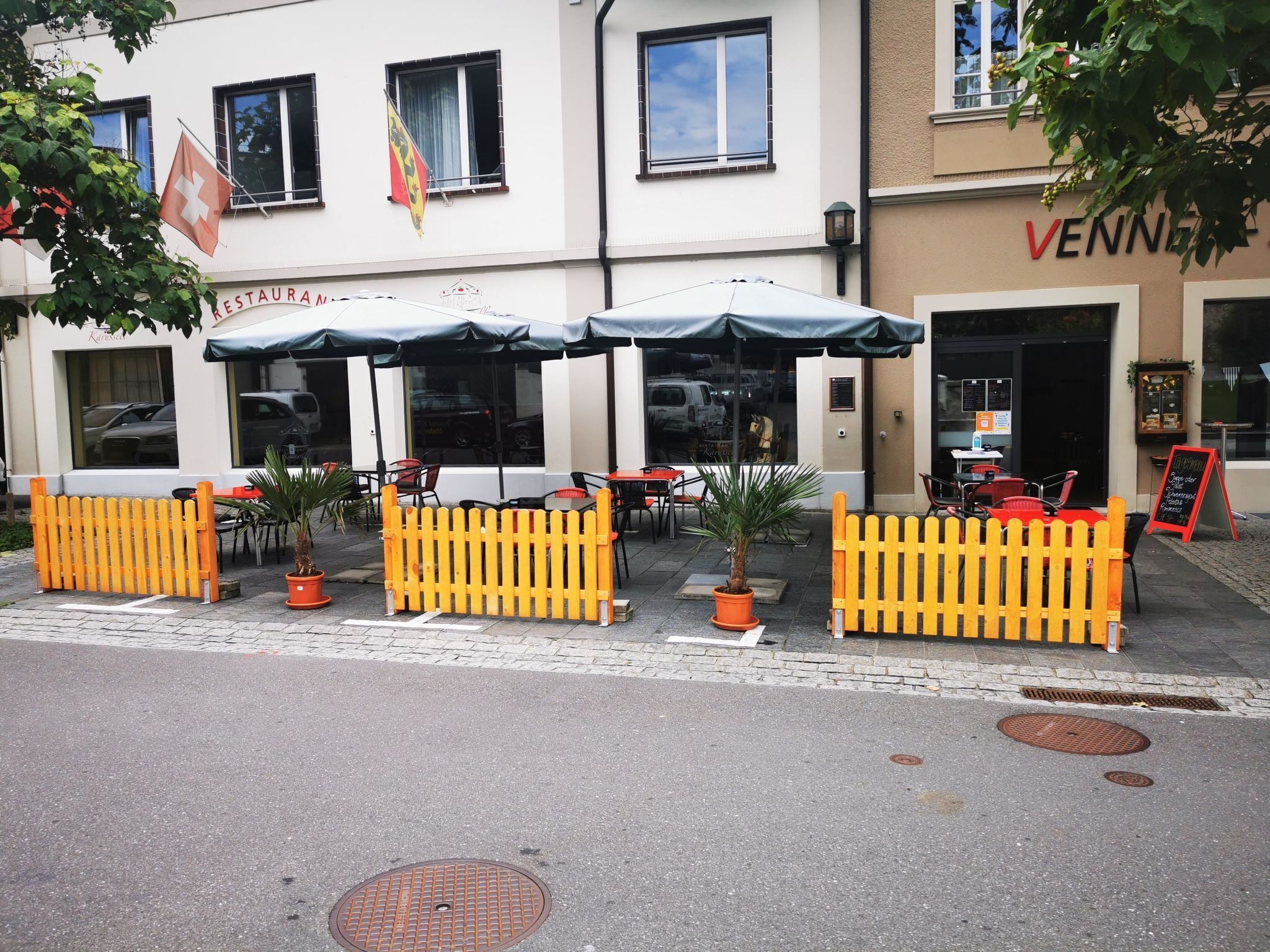 A restaurant with outdoor seating, a Swiss flag, and a sign for 'VENNER'.