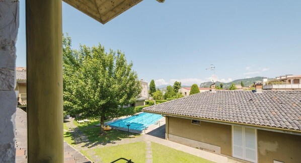 Zona residencial con piscina, un árbol y un edificio con techo de tejas.