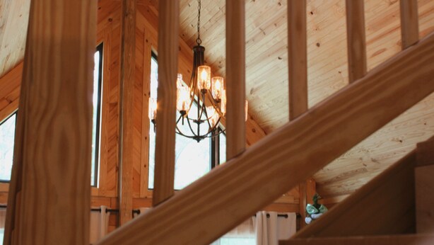 A wooden staircase with a chandelier. - Rustic and Elegant Creekside Log Cabin (Wing)