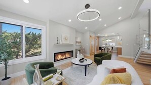 A modern living room with a fireplace, a dining area, and a staircase leading to an upper level. - 25. 4BR Coastal Oasis Near Legoland and Beach (Carlsbad)
