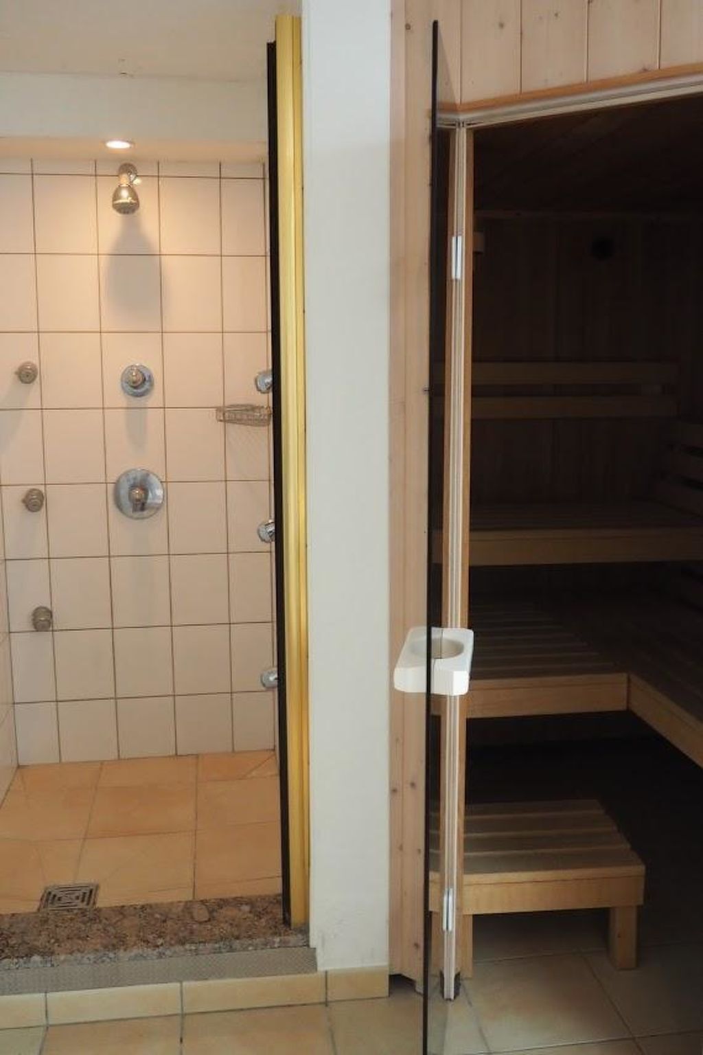 Una habitación con ducha, un banco de madera y una puerta blanca.