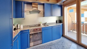A modern kitchen with blue cabinets, stainless steel appliances, and a granite countertop. - Snow-Fun B Penthouse Appartement/Fewo Appartement/Fewo by Interhome (Saas-Fee)