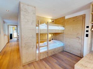 A room with a bunk bed, wooden walls, a door with a handle, and a small table. - Alphubel Peak & Unlimited Appartement/Fewo Peak 05 by Interhome (Saas-Fee)