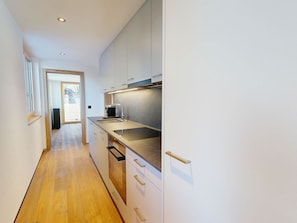 A modern kitchen with a stainless steel sink, a coffee machine, and a view into the adjacent living area. - Alphubel Peak & Unlimited Appartement/Fewo Peak 05 by Interhome (Saas-Fee)