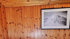 Une pièce de style cabane en bois, avec un lit, une table de chevet et une photographie encadrée accrochée au mur.