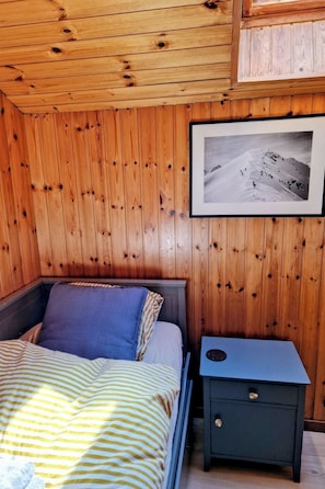 A wooden cabin room with a bed, a nightstand, and a framed photograph on the wall. - Faderhorn 8 Appartement/Fewo Appartement/Fewo by Interhome (Saas-Almagell)