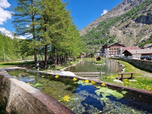 Un poble de muntanya amb un llac tranquil, passeres de fusta i edificis tradicionals.