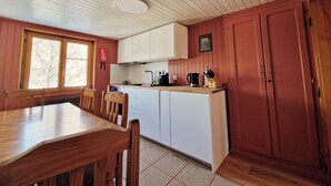 Une cuisine de taille réduite, avec des meubles de rangement en bois, une table à manger et des chaises.